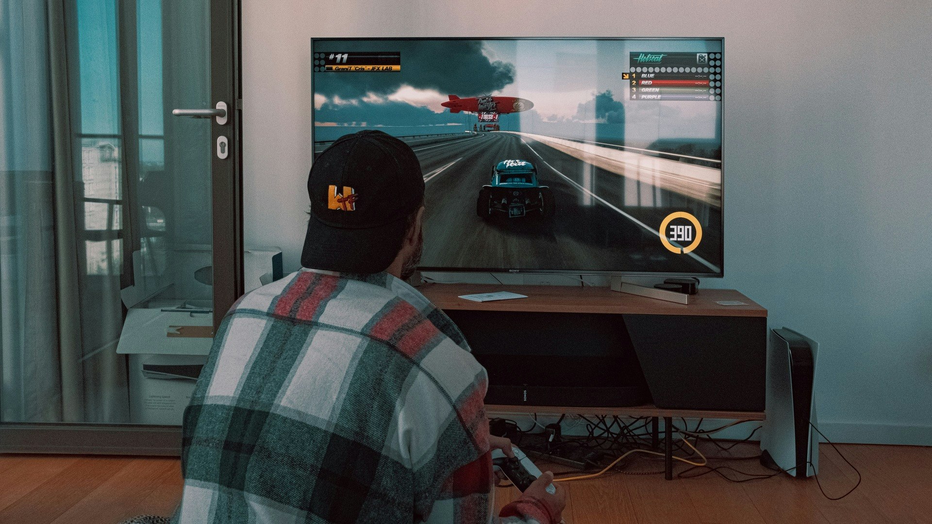 A man playing a PS5 racing game on a TV